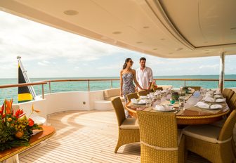 charter guests prepare to dine on the alfresco dining area on the upper deck aft of luxury yacht Mine Games