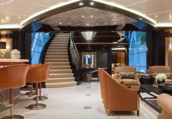 bar and seating area with staircase and piano in the background on board motor yacht Kismet