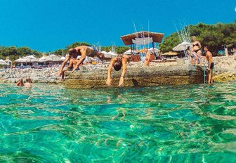 visitors at Carpe Diem Beach dive into turquoise waters in Hvar, Croatia