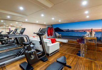 gym equipment, bar and seating area in the beach club of luxury yacht G3