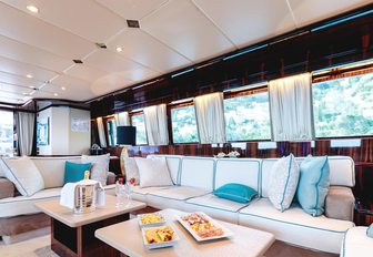 Main salon of superyacht HEMILEA, with white sofas with turquoise cushions and wide windows to let light in