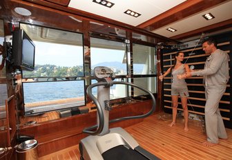 charter guest works out alongside personal trainer in the gym aboard charter yacht HANA 