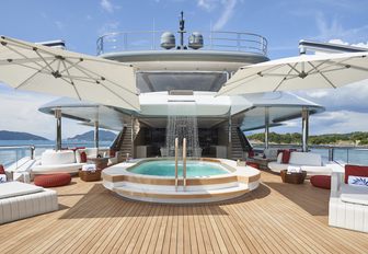 Aft deck pool and waterfall feature on board luxury yacht DAR, with surrounding seating 