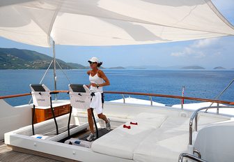A charter guest dressed in white uses a treadmill on the exterior of luxury yacht Lady J
