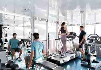 guests ona  luxury yacht charter keeping up with their gym and fitness routine in charter yacht titania well equipped gym 