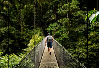 Man walking on a hanging bridge in Arenal Volcano National Park in Costa Rica