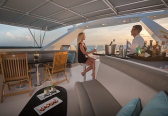 charter guest sips cocktails at the bar on the bridge deck aboard luxury yacht UNBRIDLED 