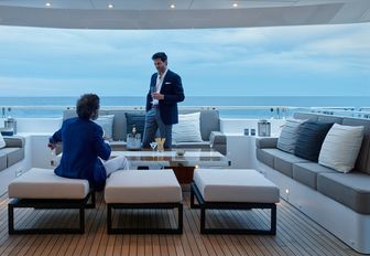 two gentlemen enjoy drinks in the alfresco lounge on the main deck aft of motor yacht ASYA 