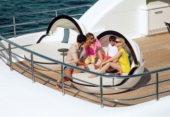charter guests hang out on one of the day beds on the sundeck of motor yacht RUYA 