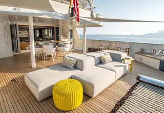 al fresco dining table and lounging area on the large aft deck of charter yacht Zulu