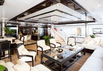 deep sofas and arm chairs form a luxe seating area on the main deck aft of charter yacht Illusion V 
