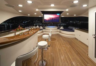 bar with stools and drop-down TV on the sundeck of charter yacht Lady Leila at night
