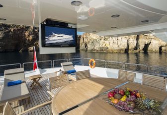 A retractable television screen next to the alfresco dining section of M/Y RINI