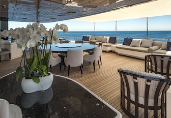 circular alfresco dining table and sofas on the upper deck aft of charter yacht RARITY