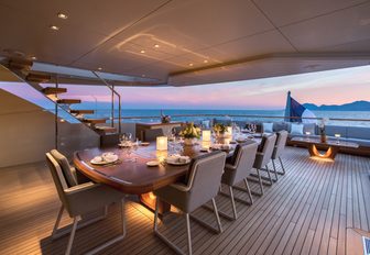 large alfresco dining area for 14 guests on the upper deck aft of motor yacht VERTIGE at sunset