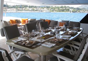 alfresco dining table and lounging area aft aboard upper deck aft of charter yacht ‘Costa Magna’