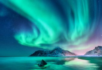northern lights above snow-covered, rugged islands in Norway