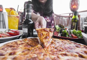Close-up shot of man reaching for slice of pizza at Diablito in Yas Marina