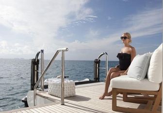 woman sits on expansive beach club on amels superyacht lady e
