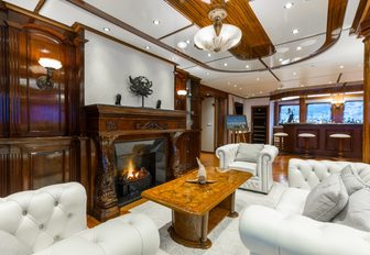 sofa and armchairs face a fireplace in a salon aboard luxury yacht LEGEND
