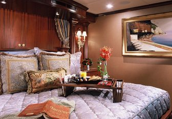 detailed shot of breakfast on tray on plush bedspread in cabin of luxury charter yacht alessandra, with rose in vase and book next to it