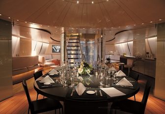 curved dining salon with black table set for dinner aboard luxury yacht PANTHALASSA 