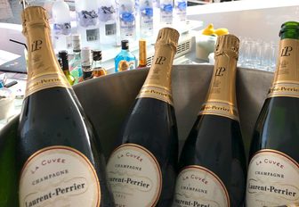 Four bottles of Laurent Perrier champagne in a bucket, vodka bottles behind