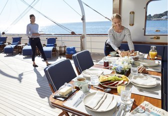 crew members get alfresco dining area ready for lunch on board luxury yacht MALAHNE