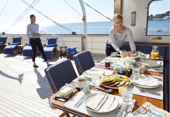 crew members get alfresco dining area ready for lunch on board luxury yacht MALAHNE