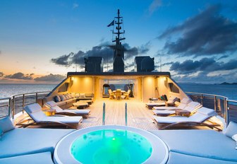 Sunloungers on deck of O'MEGA superyacht with soft lighting at sunset