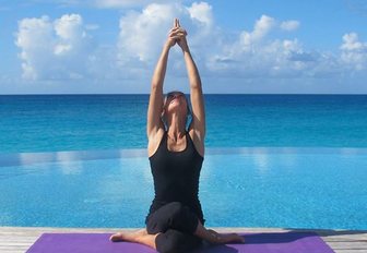 woman sitting in meditative yoga position reaching her arms up to the sky in zen