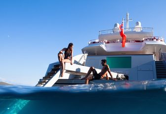 charter guests relax next to the water on the swim platform on board luxury yacht AXIOMA 