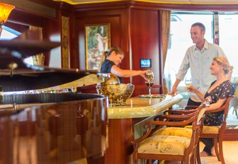 guests are served a drink at the bar next to a piano in the skylounge of luxury yacht Amarula Sun 