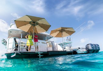 charter guests stand on the umbrella-shaded swim platform of motor yacht Remember When