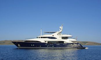 Charter yacht GRANDE AMORE at anchor, surrounded by sea with land in the distance.
