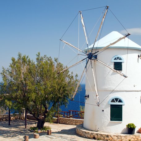 A white windmill with the sea in the background, in the Ionian Islands