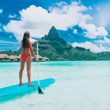 A female charter guest paddleboarding in the waters surrounding Tahiti