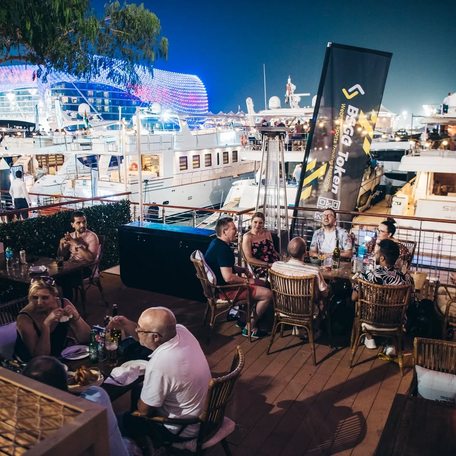 Diners at table in Diablito Yas Marina, with superyacht charter in background