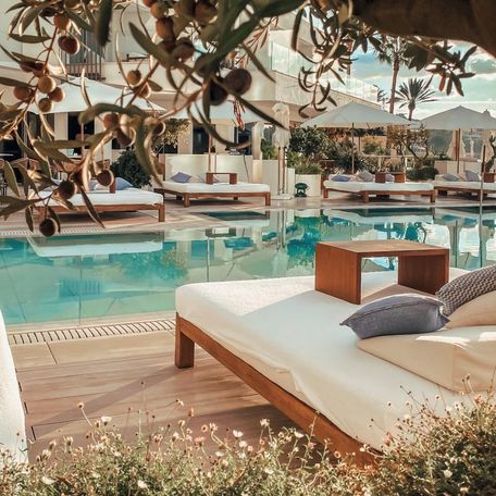 Daybeds with tables line the poolside 