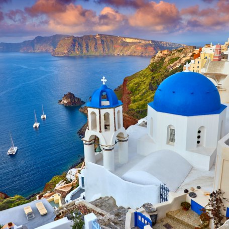 Elevated view looking down over a byzantine church and white-washed buildings in Santorini