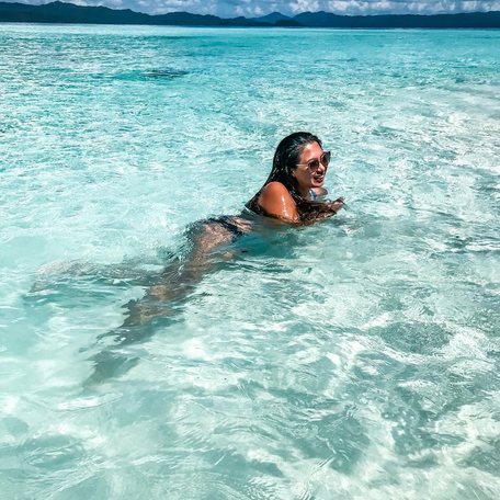 Woman in black bikini swimming in crystal clear blue water 