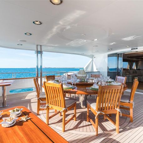 Alfresco dining area onboard charter yacht MISS STEPHANIE, dining table and chairs situated adjacent to doors leading to interiors.