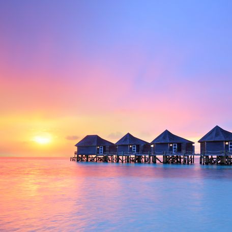 Wooden beach huts in the Maldives at sunset