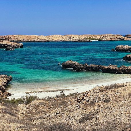 Rocks surround a small white sand beach with vibrant blue waters 