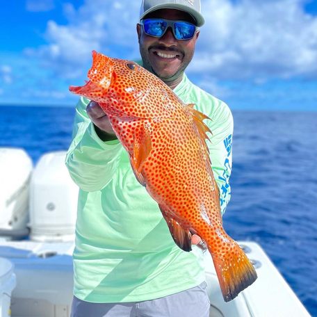 Man holding up orange fish he has caught 