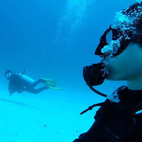 Two scuba divers in light blue waters 