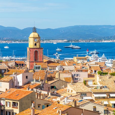 Elevated view looking over the rooftops of Saint Tropez, with charter yachts in the bay