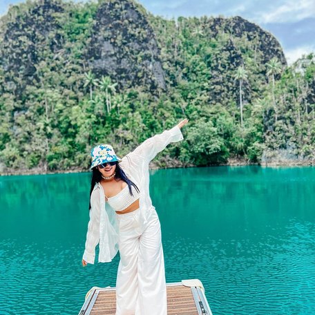 Girl in white outfit balancing on pontoon over jade green waters