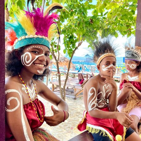 Three villagers in traditional dress and body paint 