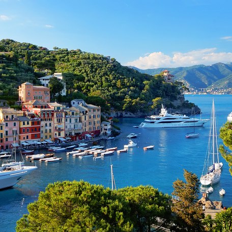 Elevated view looking down at the coastline of Portofino with colored buildings on the shore and yachts at anchor